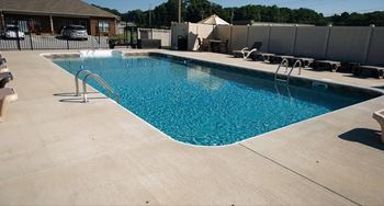 A large swimming pool with a concrete floor and a metal ladder.